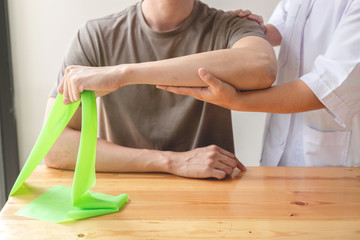 Female physiotherapists provide assistance to male patients with elbow injuries examine patients in rehabilitation centers. Physiotherapy concepts