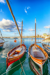 Fototapeta premium Summer view of the Alghero Marina yacht port at the Gulf of Alghero with anchored sailboats