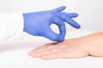 A cosmetologist doctor examines the dry and wrinkled skin on the hand of an elderly woman. The...
