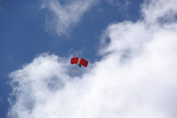 red parachute wing in a blue sky with white clouds