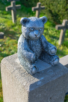Concrete statue of a little bear painted in silver with small concrete crosses in the background