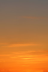 Sun below the horizon and clouds in the fiery dramatic orange sky at sunset or dawn backlit by the sun. Place for text and design.