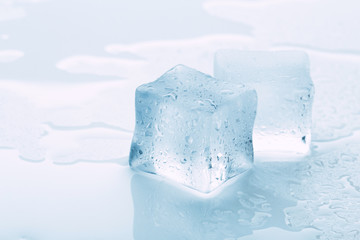 several melted ice cubes with drops on a light background with blue tinting