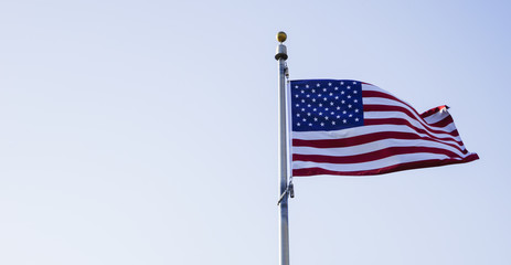 Flag of the United States is waving in the afternoon sky.