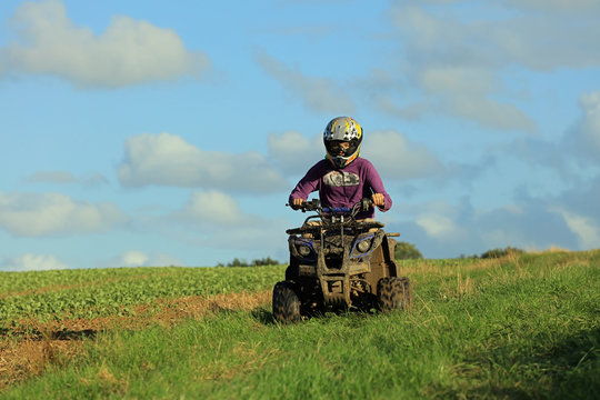 Young teenage boy riding a quad bike in the English countryside.