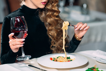Young beautiful woman eating pasta in a restaurant.