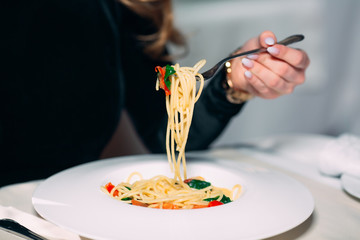 Young beautiful woman eating pasta in a restaurant.