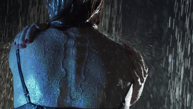 Muscular wet female back. Sexy naked female body gets wet in the rain