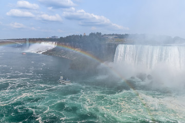 Fototapeta na wymiar Panorama of the Canadian side of the falls, with a tourist boat and rainbow. Concept of travel and tourism. Niagara Falls, Canada. United States of America