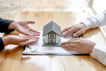A real estate agent with House model is talking to clients about buying home insurance. Home insurance concept