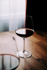 Red wine glass on a wooden table at home