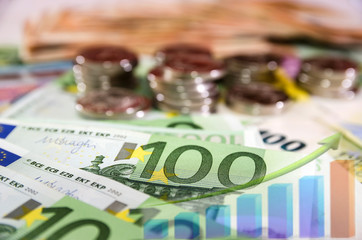 Euro banknotes on the background of coins and business charts. Economic growth, business development strategy.
