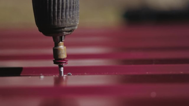 Close-up fastening red metal shingles with screws. Mount roof