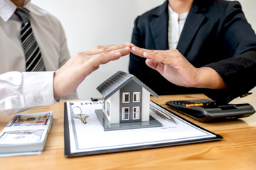 The house is covered by a  hand protecting to the client the buyer of the house in the real estate concept