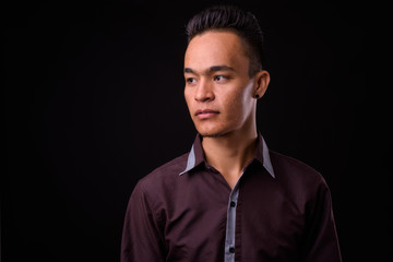 Portrait of young handsome Indian businessman thinking