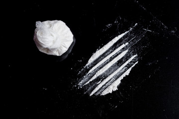 white powder (heroin, cocaine, narcotic) in a plastic bag on a black background, drugs are...