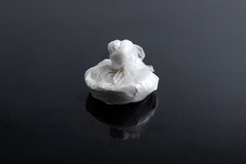 white powder (heroin, cocaine, narcotic) in a plastic bag on a black background