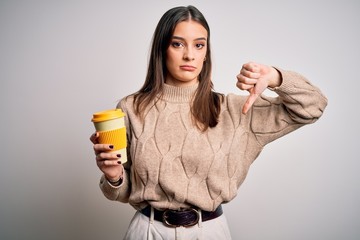 Young beautiful brunette woman drinking glass of coffee over isolated white background with angry...