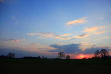 Obraz na płótnie Canvas Kolorowy zachód słońca nad obszarem wiejskim, złote chmury.