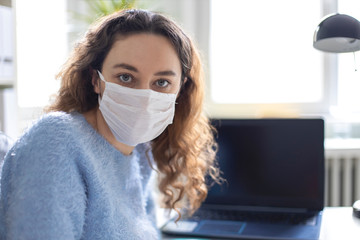 Young business woman working from home wearing protective mask