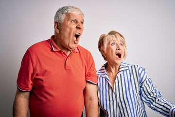 Senior beautiful couple standing together over isolated white background angry and mad screaming frustrated and furious, shouting with anger. Rage and aggressive concept.