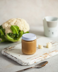  Closed glass jar with baby food smoothie puree on a wooden board. Layout Baby food concept, first feeding.