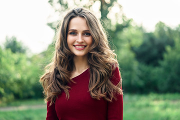 Naklejka premium Portrait of young beautiful woman outdoors on green summer nature background