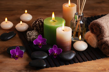 Fototapeta na wymiar Aromatherapy, spa, beauty treatment and wellness background with massage stone, orchid flowers, towels and burning candles...