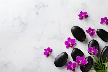 Spa composition with flowers, green leaves and massage stone on white background top view. Beauty treatment and relaxation concept. Flat lay. .