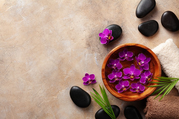 Obraz na płótnie Canvas Beauty, spa background with massage stone and flowers on brown background top view. Relaxation and wellness concept. Flat lay.