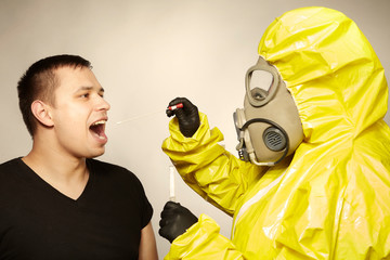 Specialist in virus protective suit getting mucous membrane smear for testing