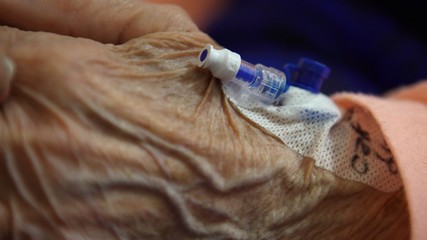 Intravenous cannula placed in the hand of an elderly patient for palliative care of a terminal...