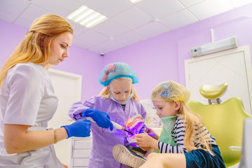 Dentist teaches children how to treat teeth.