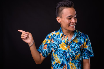 Portrait of happy young Indian tourist man pointing to the side