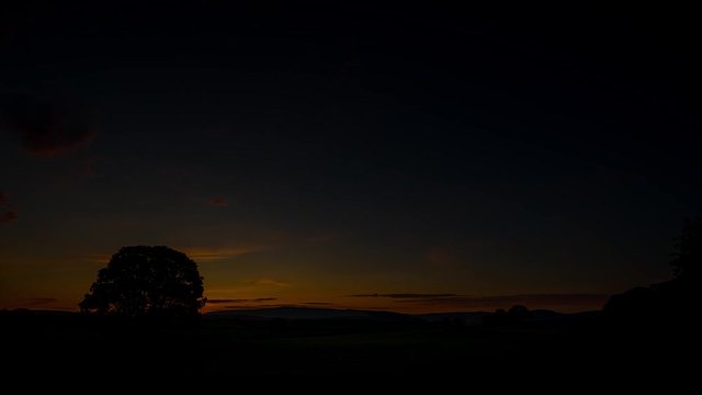 Timelapse of a sunrise over a tree on farmland near malham, Yorkshire Dales National Park, UK