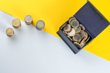 Small chest box full of euro coins, white and yellow background. Concept of accounting, savings, economy and finance.