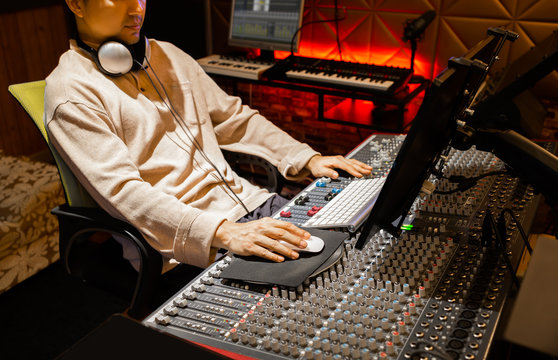 asian male producer, sound engineer working on computer and mixing console in recording studio. music production, recording concept