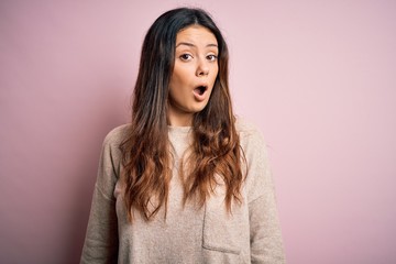 Fototapeta premium Young beautiful brunette woman wearing casual sweater standing over pink background In shock face, looking skeptical and sarcastic, surprised with open mouth