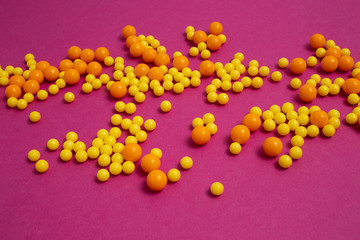 bunch of colorful pills for viral diseases. Prevention of influenza, coronavirus, covid-19. handful of yellow, orange vitamins on purple background. medical healthcare concept. flatlay, top view