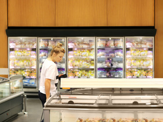 Woman choosing frozen food from a supermarket freezer	