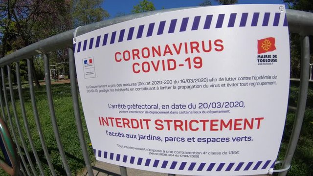 Coronavirus (COVID-19) Sign on Metal Barrier Blocking Entrance To Children's Park on a Beautiful Spring Day in Toulouse, France