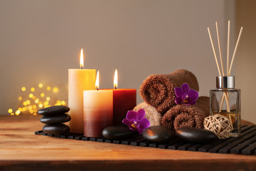 Spa, beauty treatment and wellness background with massage stone, orchid flowers, towels and burning candles.