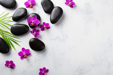 Fototapeta na wymiar Spa composition with flowers, green leaves and massage stone on white background top view. Beauty treatment and relaxation concept. Flat lay. .