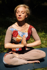 Caucasian woman yoga meditating sitting lotus, hands coupled.