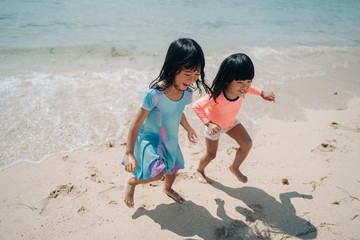 Fototapeta na wymiar two little Asian girls playing on the beach enjoying the pleasure of vacationing