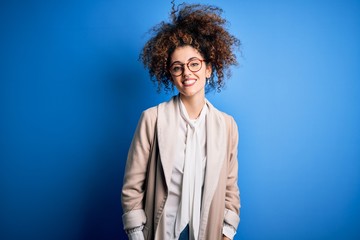 Fototapeta na wymiar Young beautiful businesswoman with curly hair and piercing wearing jacket and glasses with a happy and cool smile on face. Lucky person.