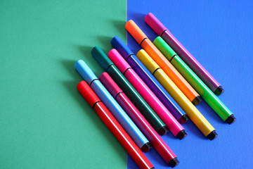 Set of colored markers on a green-blue background. All the colors of the rainbow. Office and school supplies.