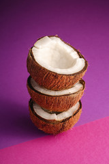 Stacked coconut fruits on violet and purple plain background, abstract food tropical concept, angle...