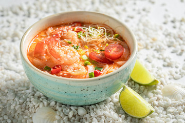 Delicious Tom Yum soup in blue bowl with lime