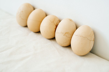 five Easter eggs trendy pastel colored with cracked shells on a white table against a white wall. minimal style. Easter concept.copy space for text
